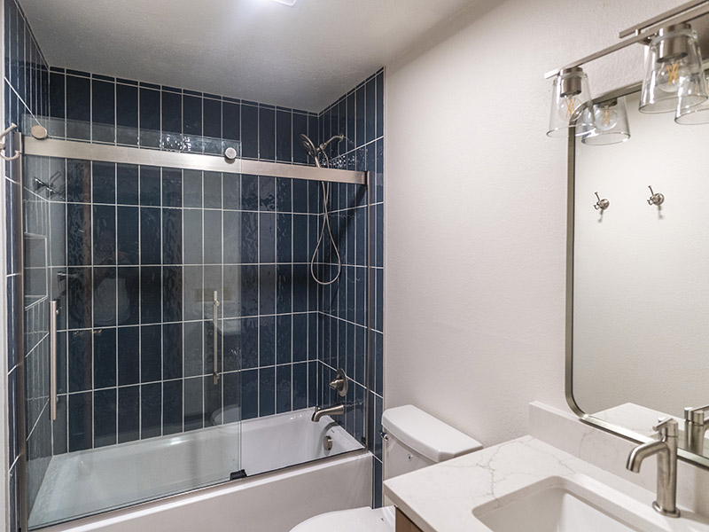 Complete Bathroom Remodel Featuring; Custom Vanity with Quartz Countertop, Brushed Chrome and Glass Shower Doors, Blue Vertical Set Porcelain Tile Shower Walls